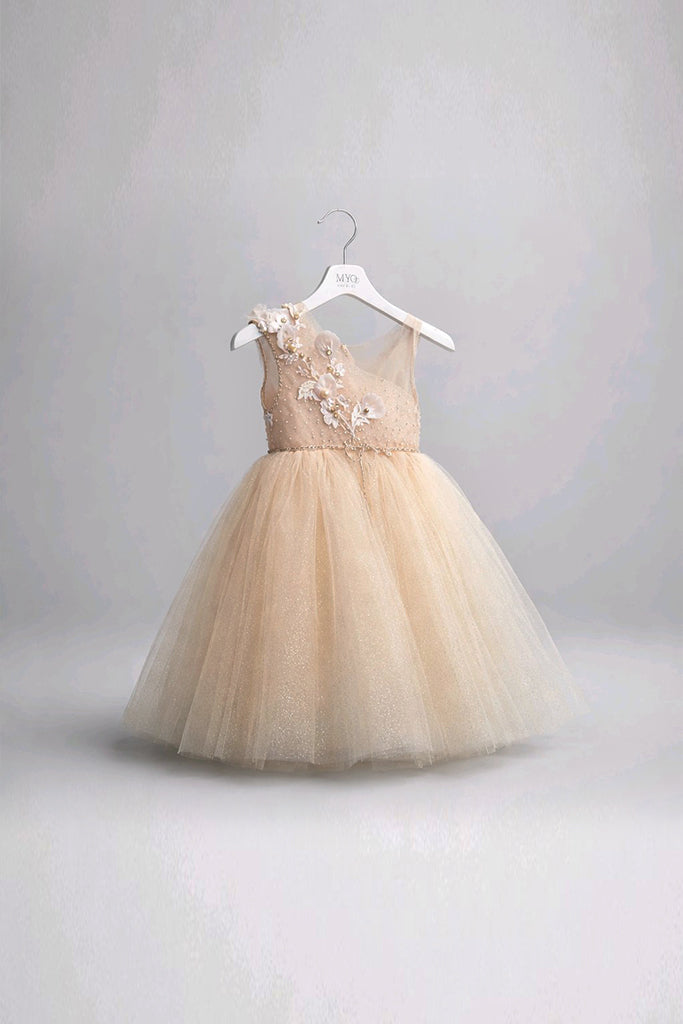 A toddler girl's couture dress in a soft champagne beige tulle, featuring a sleeveless bodice with floral applique and a full tulle skirt.