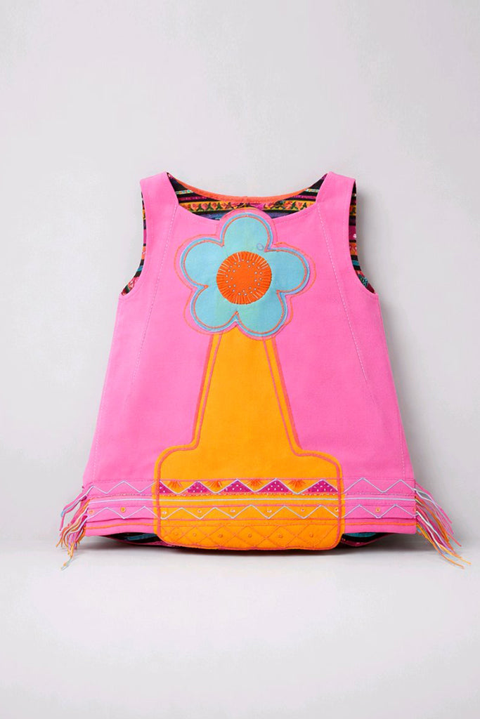 A sleeveless pink vest with colorful applique details, featuring a large flower motif on the front in light blue and orange, and a yellow-orange textured pouch at the bottom. The vest has fringe on the sides and a patterned inner lining visible at the armholes.