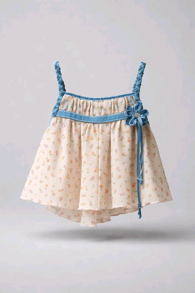 A baby girl's tiered dress with a cream-colored floral print, a blue waistband, and braided shoulder straps.