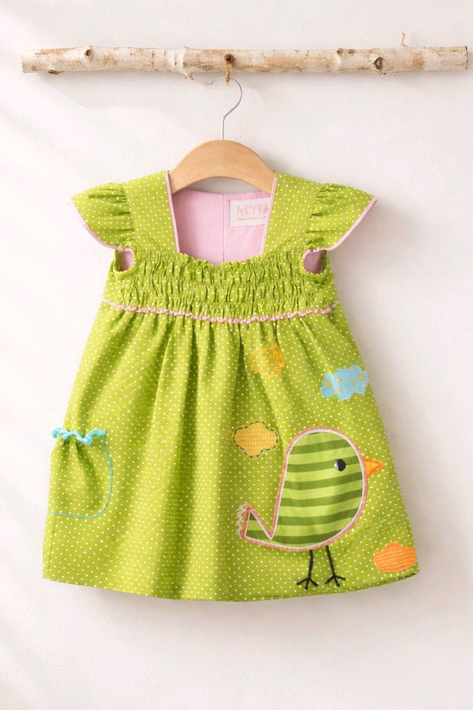 A green children's dress with white polka dots, featuring a cartoon bird applique on the front.
