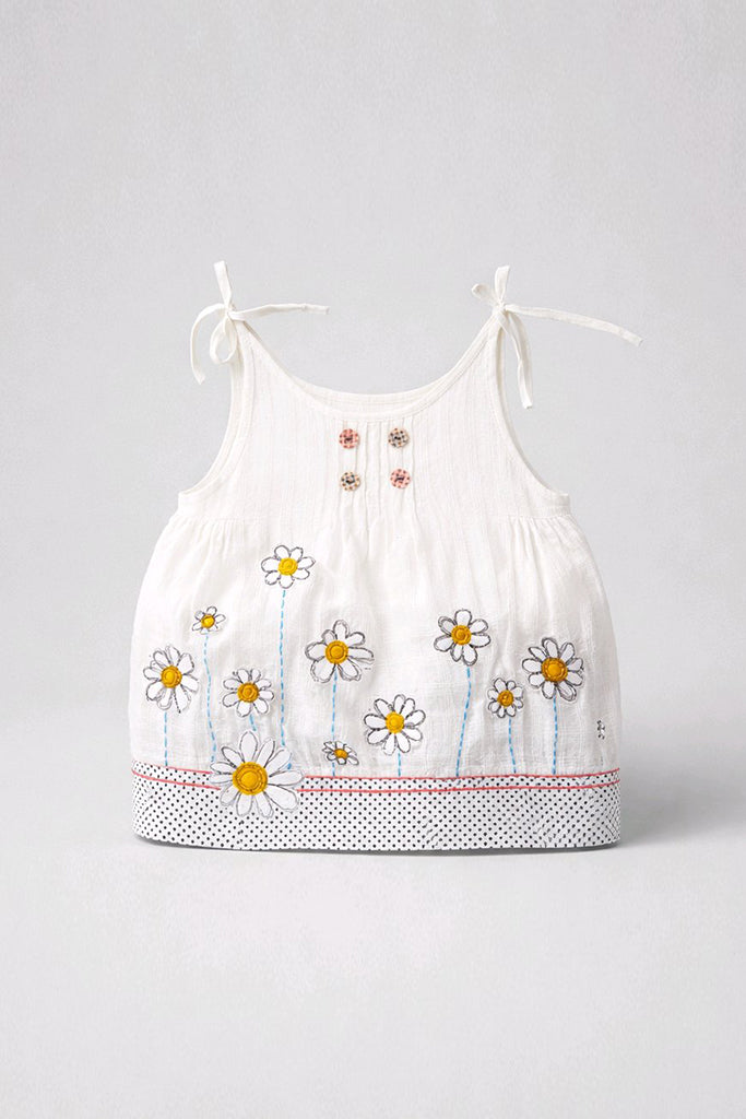 A white sleeveless baby top with delicate tie straps, featuring embroidered daisy flowers and a small bee on the front, finished with a polka dot hem.