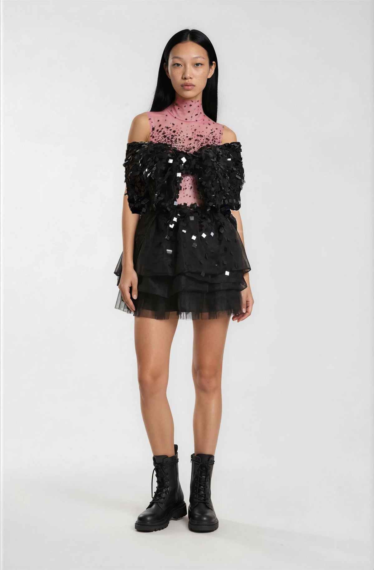 Model wearing a black sequin top and skirt with a pink lace top underneath.