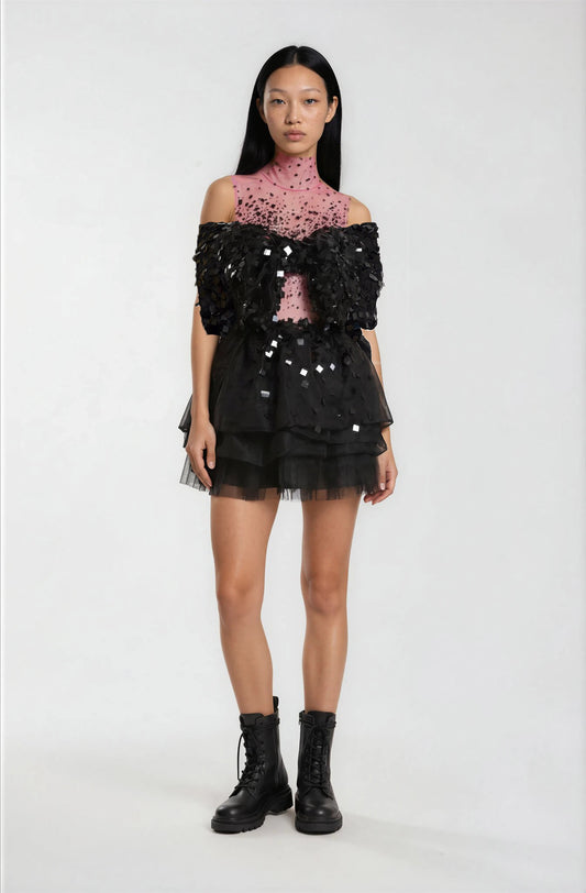 Model wearing a black sequin top and skirt with a pink lace top underneath.