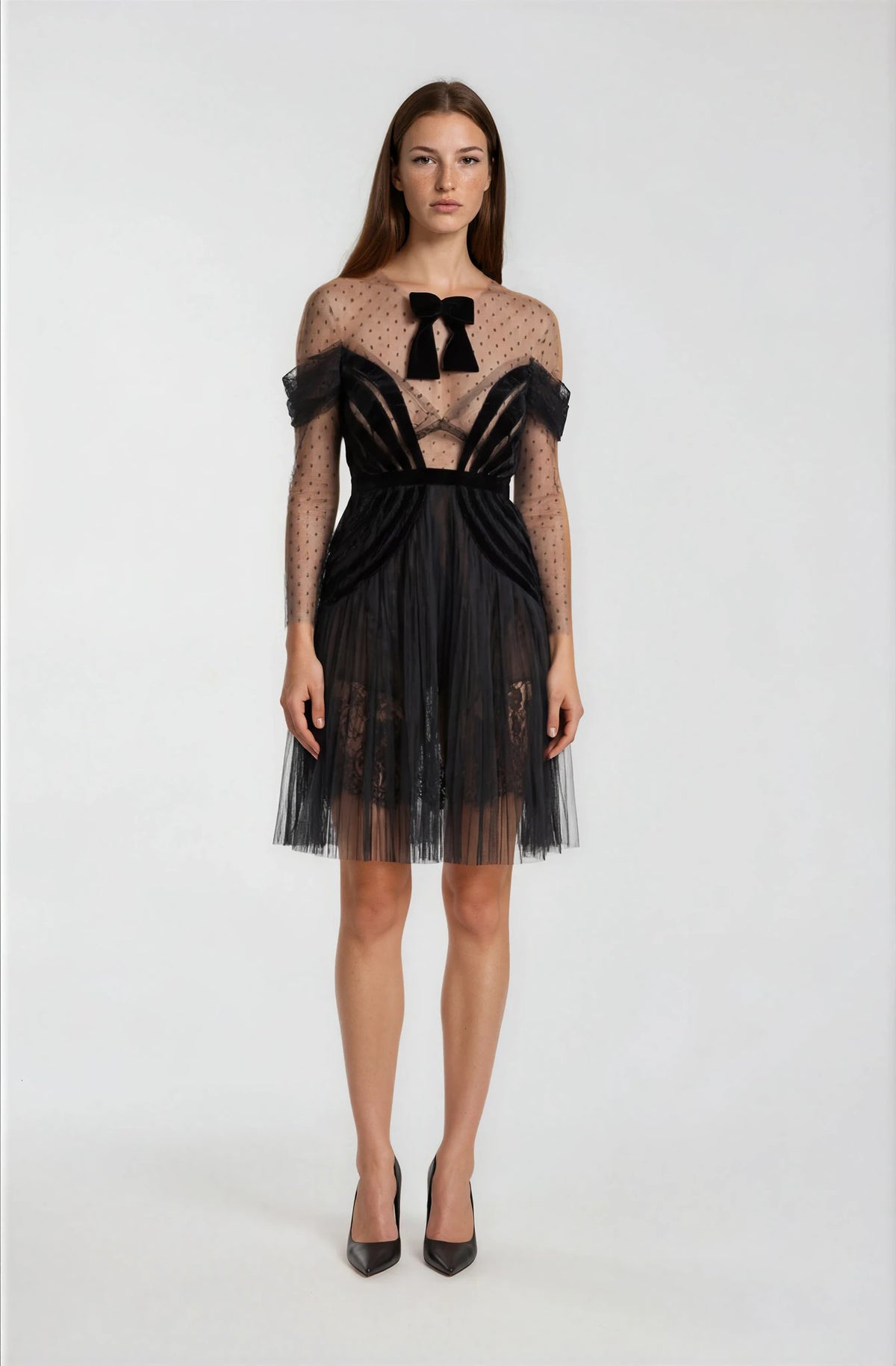 Woman wearing a black and sheer dress with bow details.