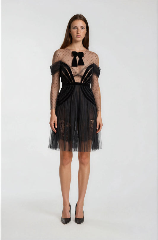 Woman wearing a black and sheer dress with bow details.