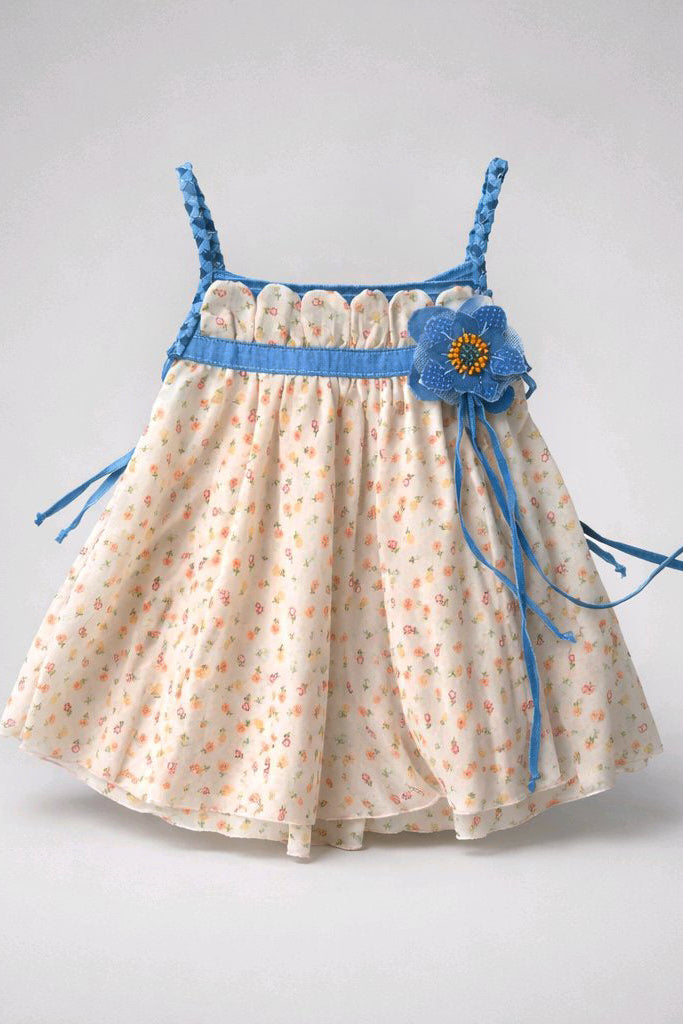 A toddler girl's sleeveless dress with a cream-colored fabric in small orange and blue floral prints, featuring a bright blue waistband, braided shoulder straps, and a decorative blue flower applique. 