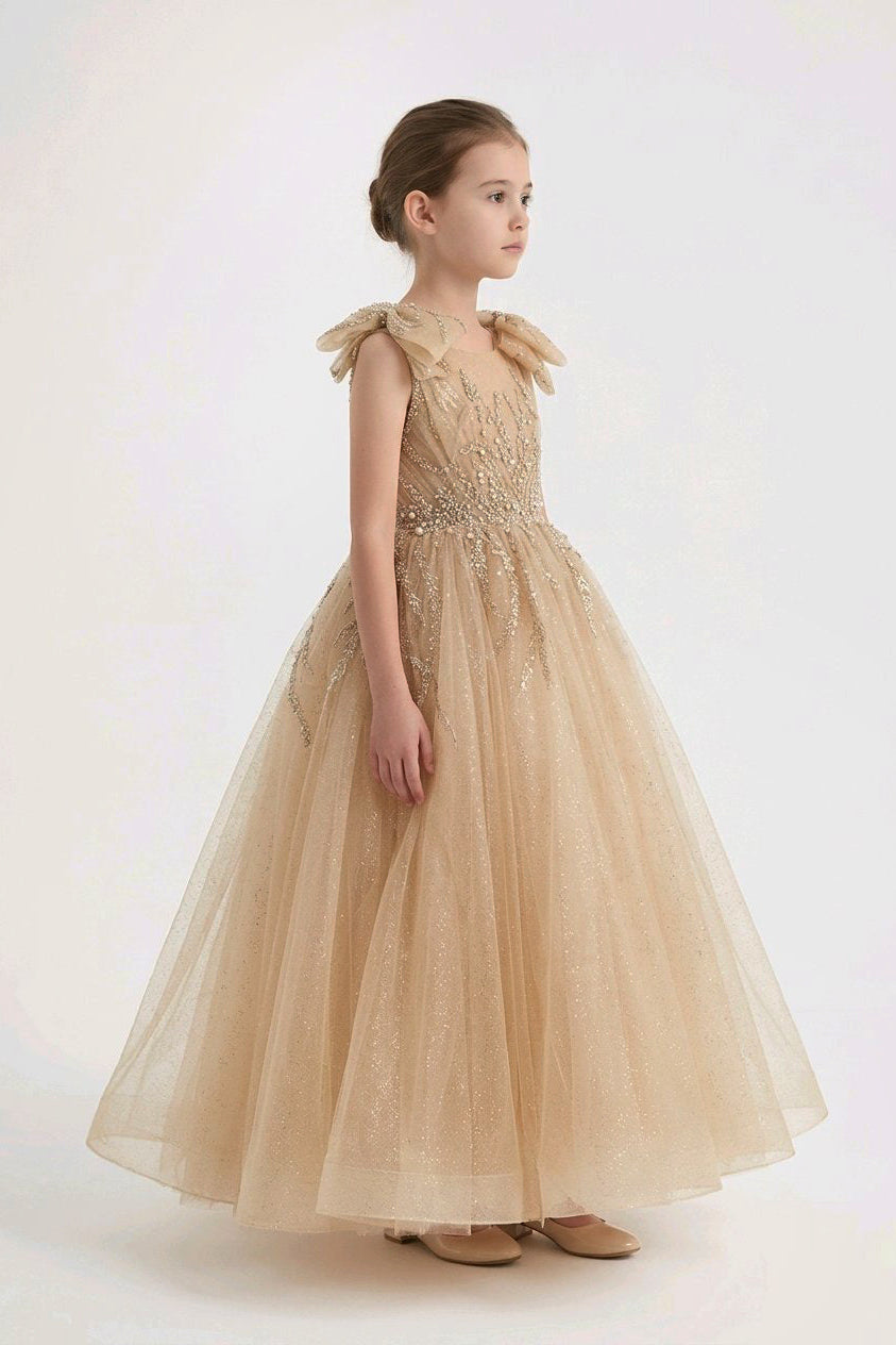 A champagne beige tulle ball gown with intricate beadwork on the bodice and bow details on the shoulders.