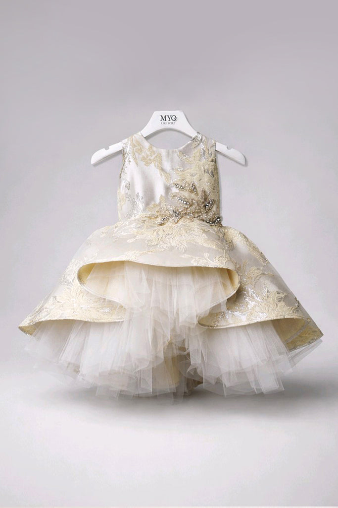 A sleeveless Jacquard Baby Dress
featuring a champagne-gold embroidered bodice, a layered ruffled skirt in champagne and ivory, and a tulle underskirt. 