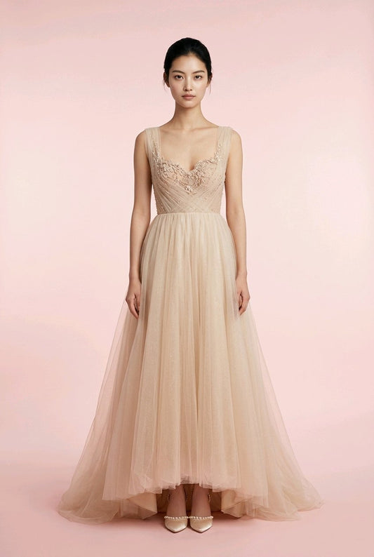 Woman wearing a beige evening gown with intricate detailing.