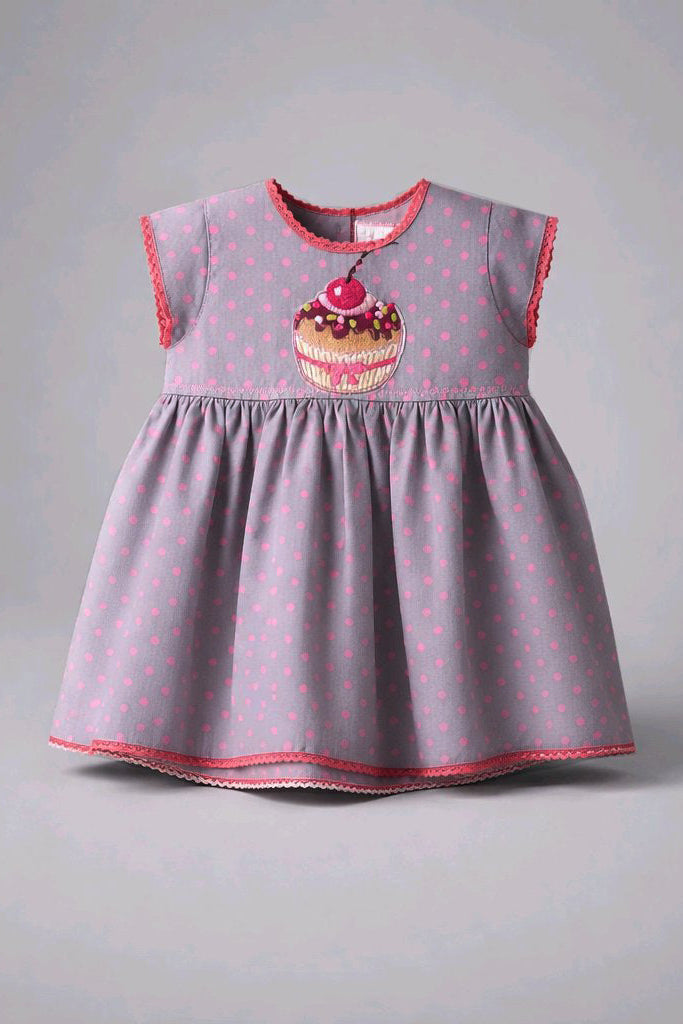 A baby girl's sleeveless dress in light purple with pink polka dots, featuring a cupcake graphic on the chest and pink trim along the neckline, armholes, and hem.
